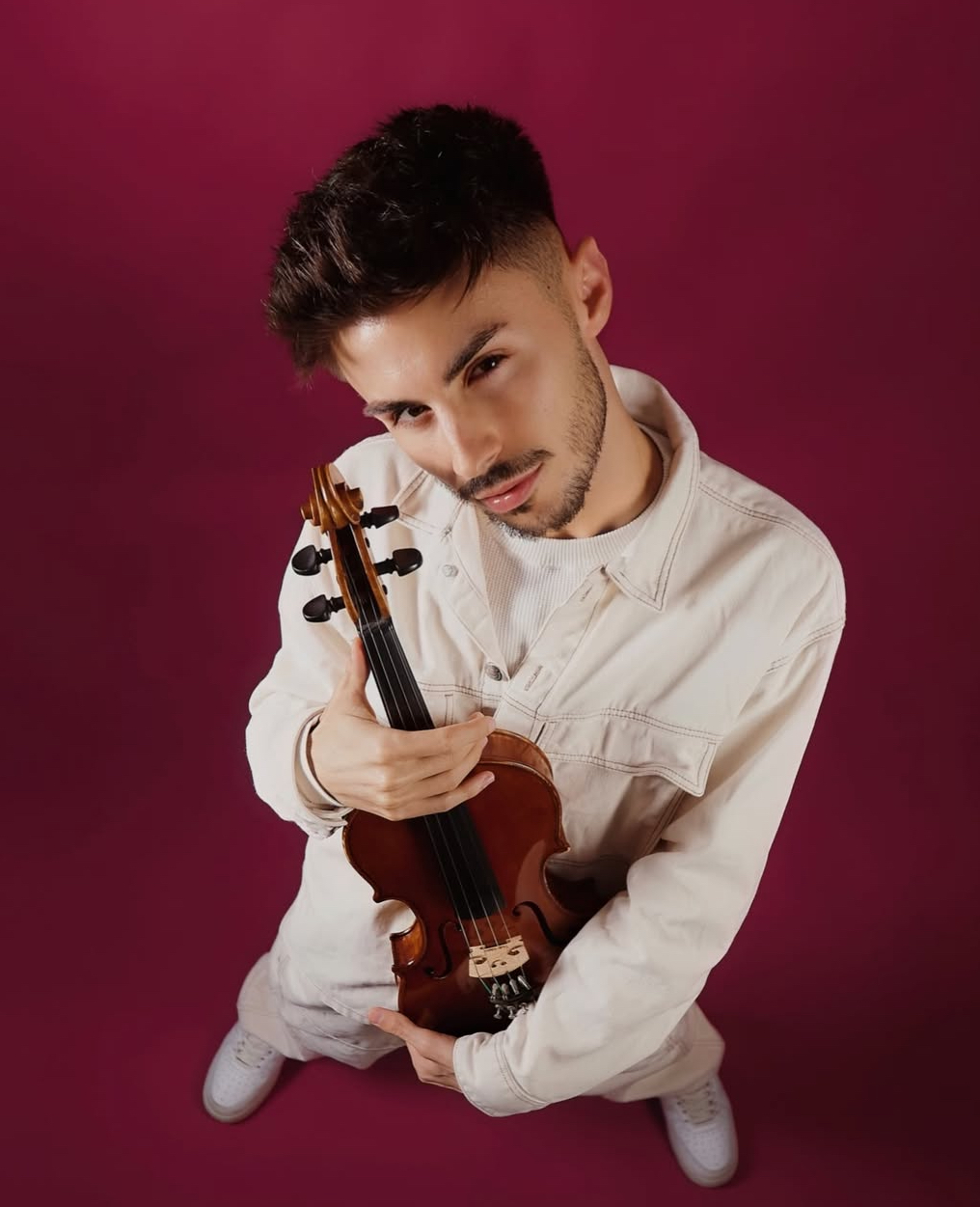 Máté Kozma studio portrait on burgundy background holding violin